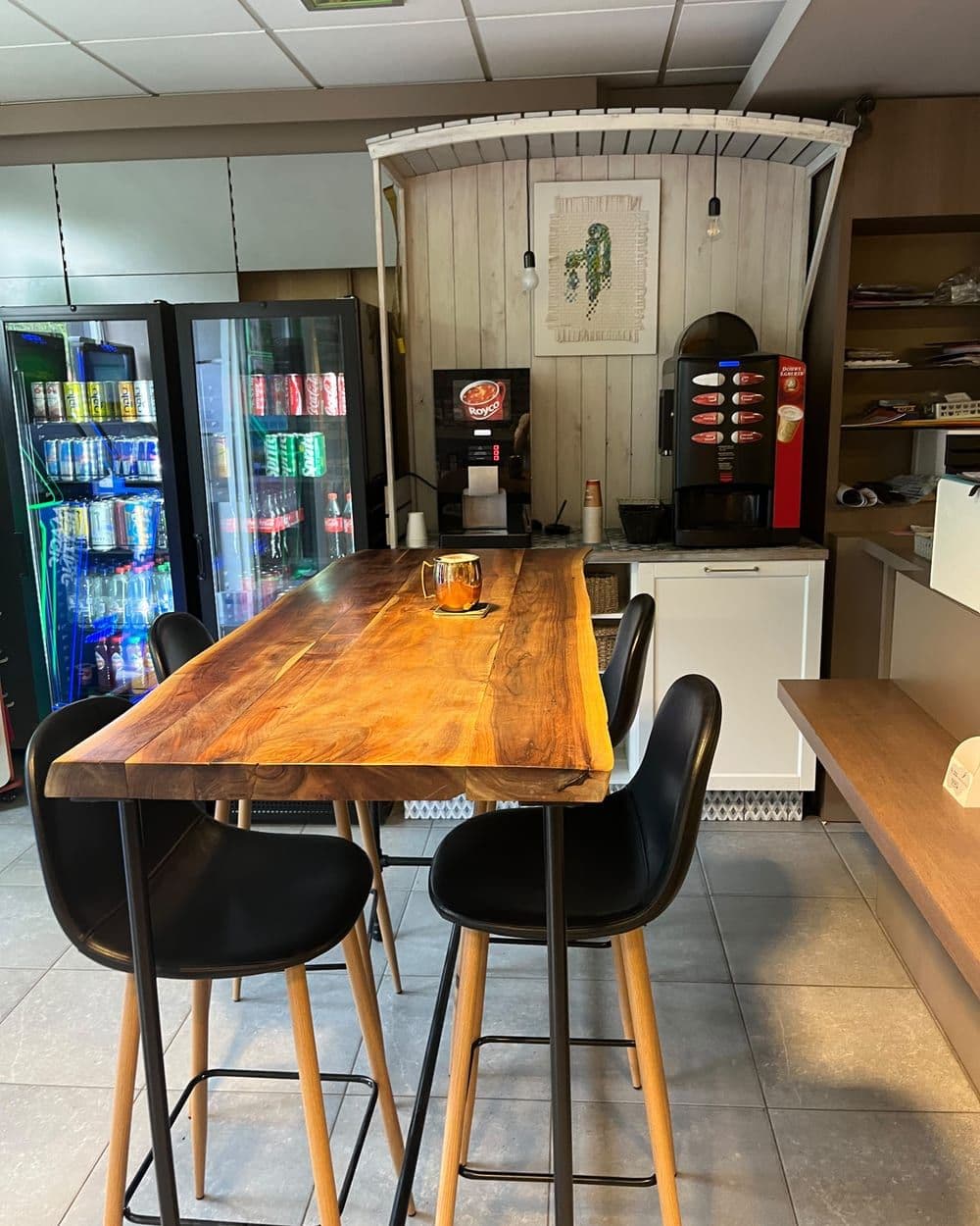 De houten tafel met krukken, naast het koffieapparaat